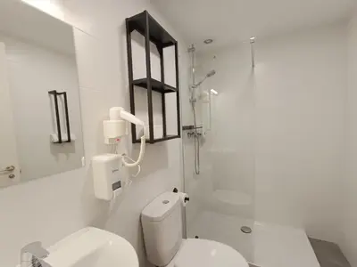 a white bathroom with a toilet and a shower at Apartamentos Turísticos Pontepedriña by Bossh! Hotels in Santiago de Compostela