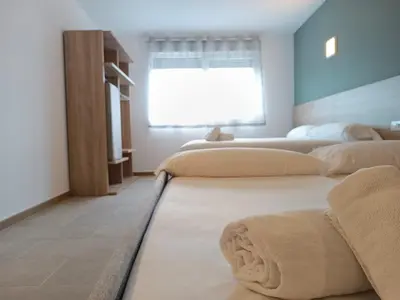 a bedroom with three beds and a window at Apartamentos Turísticos Pontepedriña by Bossh! Hotels in Santiago de Compostela