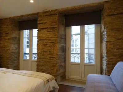 a bedroom with stone walls and a bed and windows at Apartamento foroplaza campo I in Lugo