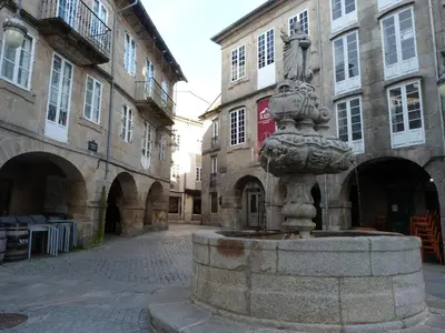 a fountain in the middle of a street with buildings at Apartamento foroplaza campo I in Lugo