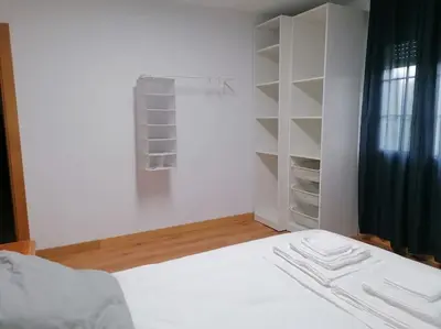 a bedroom with a white bed and a closet at Lar de Yago - Apto Ribadeo in Ribadeo