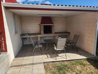 a patio with a table and chairs and a fireplace at villa requian in Cacheiras