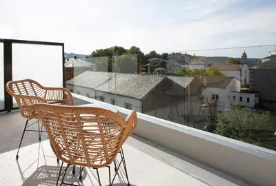 two chairs on a balcony with a view of a city at Pensión Roma in Castroverde