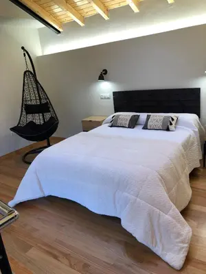 a bedroom with a large white bed and a chair at Apartamentos El Arroyo in Armal