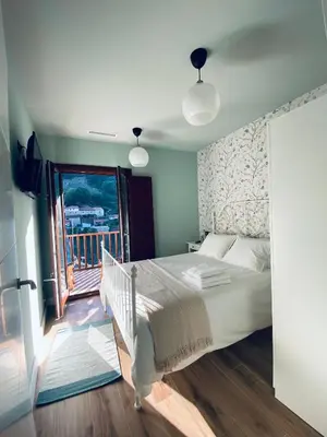 a bedroom with a large bed and a balcony at Casa Aturuxo in Belesar