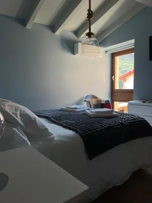 a white bed with a black blanket and a window at Casa Aturuxo in Belesar