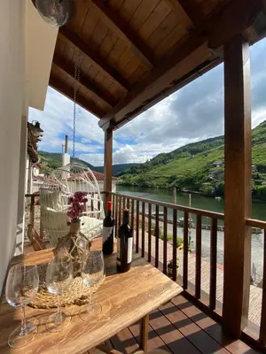a balcony with wine glasses and a view of a river at Casa Aturuxo in Belesar
