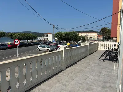 a balcony with a white fence and a street with cars at Piso primera línea playa Miño/La Coruña in Miño
