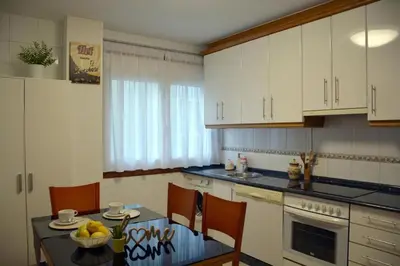 a kitchen with white cabinets and a table and chairs at HHC - Duplex Concheiros, 4 bedrooms, 3 bathroom, a 700m de la Catedral in Santiago de Compostela
