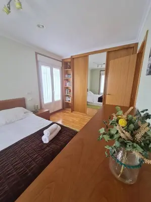 a bedroom with a bed and a vase of flowers on a table at Preciosa casa en Ribadeo in Ribadeo