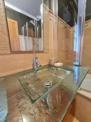 a bathroom sink with a glass counter top at Preciosa casa en Ribadeo in Ribadeo