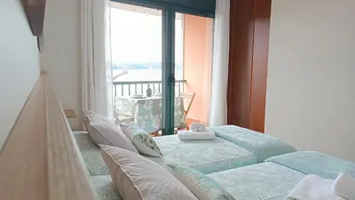 a bedroom with two beds and a large window at SALSEIRAZO - PLAYA A RIBEIRA MIÑO in Miño