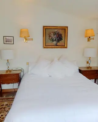 a bedroom with a white bed with two nightstands and two lamps at Sobre la Ría 2 in Viveiro