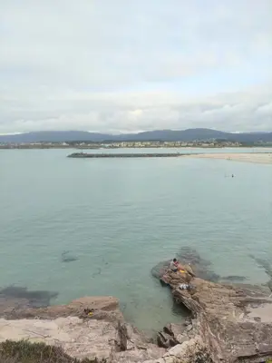 a person sitting on a rock in the water at Apartamento Tamarisco in Foz