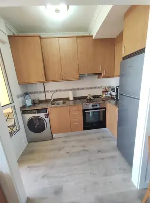 a small kitchen with wooden cabinets and a dishwasher at Apartamento Tamarisco in Foz