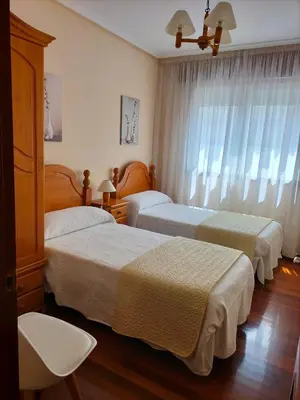 a hotel room with two beds and a window at O NOSO FOGAR in Melide