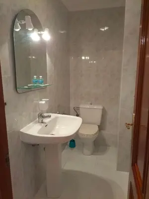 a bathroom with a sink and a toilet and a mirror at O NOSO FOGAR in Melide