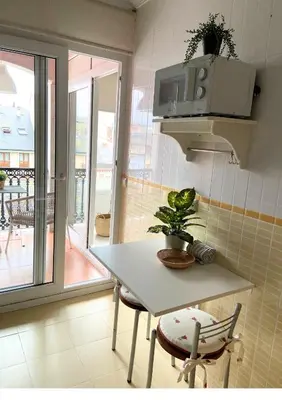 a kitchen with a white table and chairs and a window at Gran vía in Ribadeo