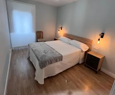 a bedroom with a large white bed and a wooden floor at Vagalume in Cervo