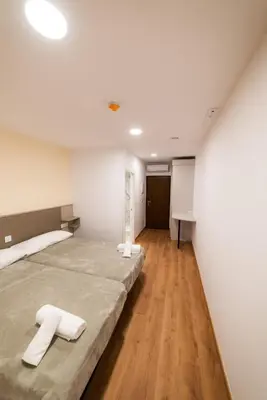 a bedroom with two beds with white walls and wooden floors at ESTRELA DO CAMIÑO in Palas de Rei