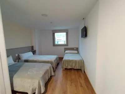 a room with two beds and a television in it at ESTRELA DO CAMIÑO in Palas de Rei