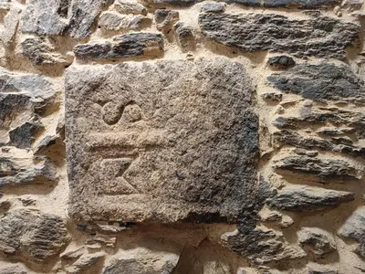 a stone sign on the side of a stone wall at Albergue SP 55 by Bossh! Hotels in Santiago de Compostela