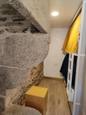 a room with a stone wall and a wooden table at Albergue SP 55 by Bossh! Hotels in Santiago de Compostela