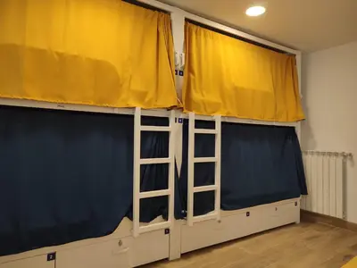 a room with two large windows and yellow curtains at Albergue SP 55 by Bossh! Hotels in Santiago de Compostela