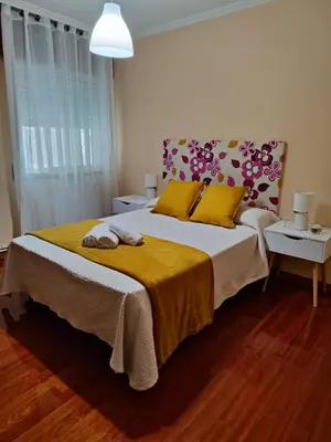 a bedroom with a large bed with a yellow blanket at Piso Pauser in Puentecesures