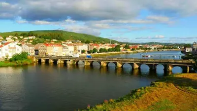 a bridge over a river next to a town at Piso Pauser in Puentecesures
