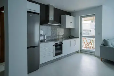 a kitchen with white cabinets and a stainless steel refrigerator at Apartamento con TERRAZA en Burela in Burela de Cabo