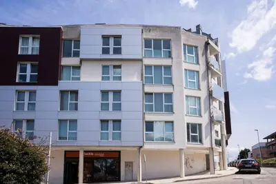 a tall white building on the corner of a street at Apartamento con TERRAZA en Burela in Burela de Cabo