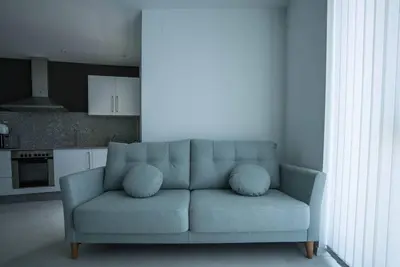 a blue couch in a living room with a kitchen at Apartamento con TERRAZA en Burela in Burela de Cabo