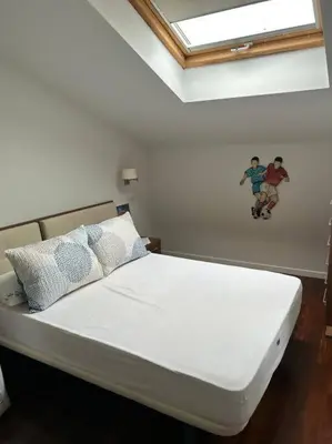 a white bed with pillows and a painting on the wall at Excepcional chalet en Perbes. in Miño