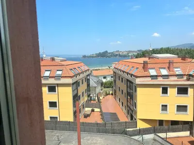 a view of two yellow buildings and the water at Playa Miño in Miño