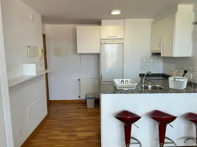 a kitchen with white cabinets and red stools at Playa Miño in Miño