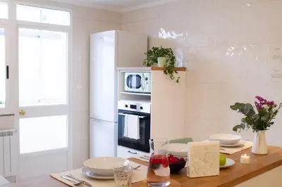 a kitchen with a wooden table with a microwave on a wall at Muralla de Tata in Lugo