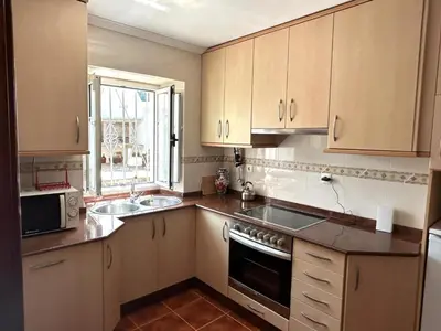 a kitchen with white cabinets and a sink and a window at Casa Pancha in Ribadeo