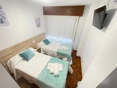 a small room with two beds and a television at Pension O Camiño Milladoiro in Amés