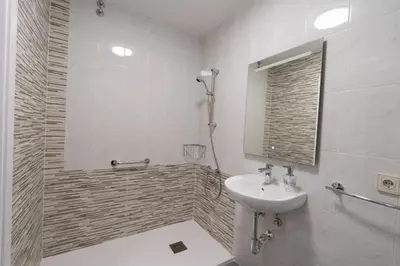 a white bathroom with a sink and a shower at Pension O Camiño Milladoiro in Amés