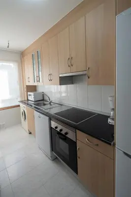 a kitchen with a black counter top and wooden cabinets at Pension O Camiño Milladoiro in Amés