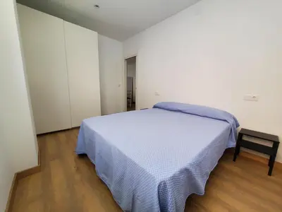 a white bedroom with a bed and a chair at BAHíA APARTAMENTOS TURÍSTICOS in Foz