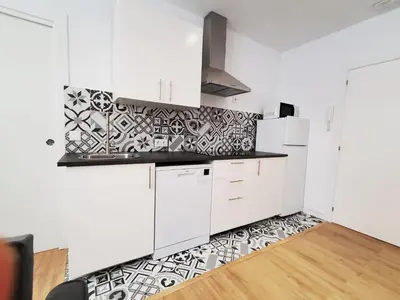 a kitchen with white cabinets and black and white tiles at BAHíA APARTAMENTOS TURÍSTICOS in Foz