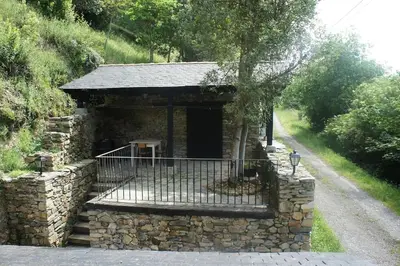 a stone building with a gate on a road at Casa Rural de montaña en LUARCA ASTURIAS in Busindre