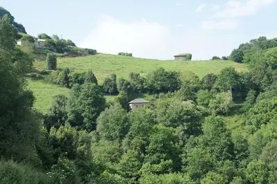 a green hill with a house on top of it at Casa Rural de montaña en LUARCA ASTURIAS in Busindre