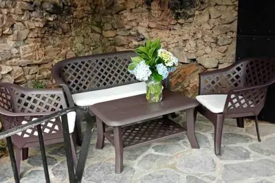 a vase of flowers sitting on a table with two chairs at Casa Rural de montaña en LUARCA ASTURIAS in Busindre