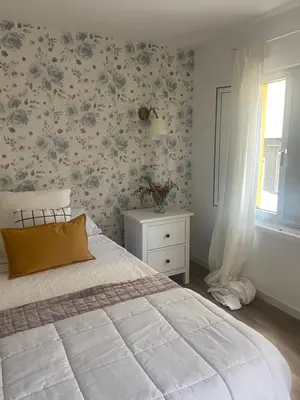 a bedroom with a bed and a window with floral wallpaper at Casita típica de pescadores -Casa Gloria- WIFI in Burela de Cabo