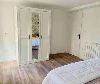 a white bedroom with a door leading to a bed at Casita típica de pescadores -Casa Gloria- WIFI in Burela de Cabo