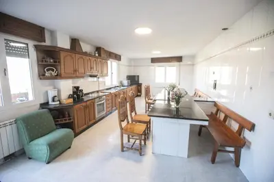 a kitchen with wooden cabinets and chairs and a counter at Pensión Lobre in O Pedrouzo