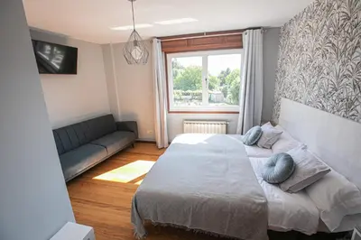 a bedroom with a large bed and a couch at Pensión Lobre in O Pedrouzo